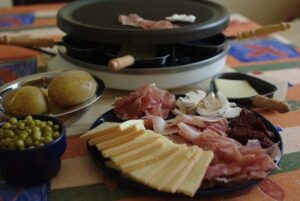 Appareil à raclette avec poêlons remplis de fromage à raclette et charcuterie
